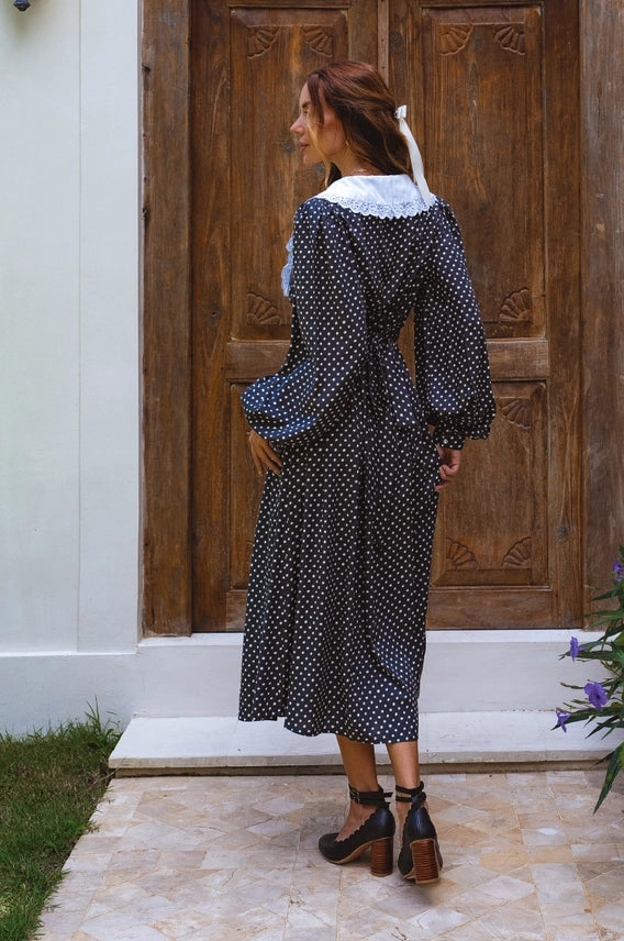 Model wearing dress from behind of black polka dot midi dress with lace collar
