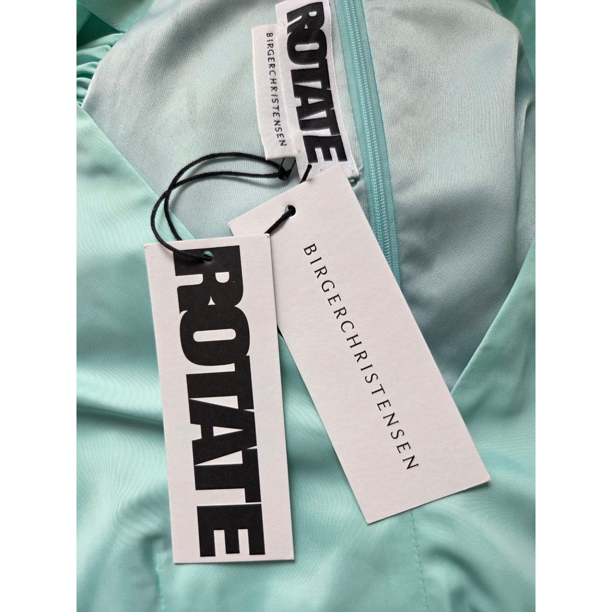 Attached retail hangtags of ROTATE Morning Mist aqua mini dress