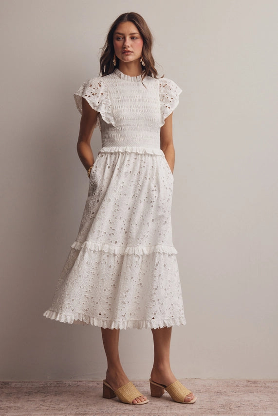 Model showing the tiered skirt of white cotton eyelet midi dress