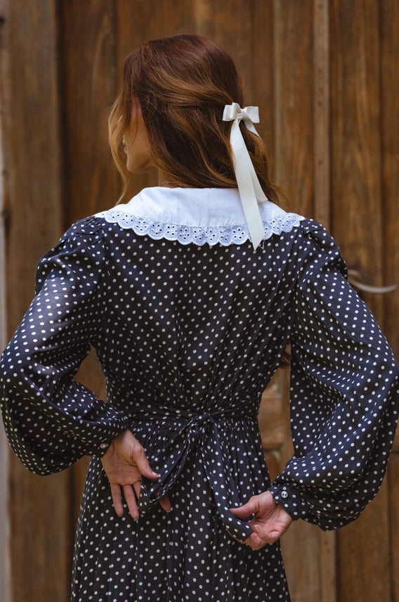Back view showing collar, sleeves and waist of black polka dot midi dress with lace collar