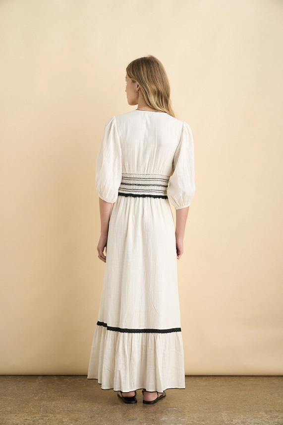 Back view of ecru maxi dress with smocked waist and black hem trim